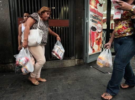 A customer leaves a private super market in Caracas, Venezuela, with her purchases, including toilet paper, on Wednesday.