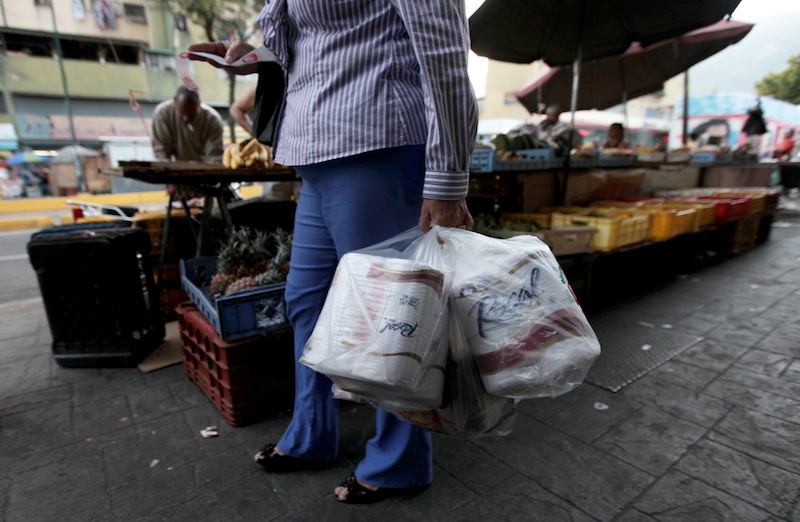 A woman who just bought toilet paper at a grocery store reads her receipt as she leaves the private store in Caracas, Venezuela, Wednesday, May 15, 2013. First milk, butter, coffee and cornmeal ran short. Now Venezuela is running out of the most basic of necessities _ toilet paper. Economists say Venezuela's shortages stem from price controls meant to make basic goods available to the poorest parts of society and the government's controls on foreign currency. (AP Photo/Fernando Llano)