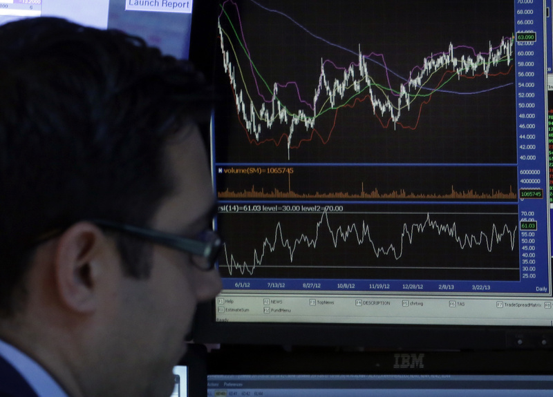 A specialist works at his post on the trading floor of the New York Stock Exchange on Tuesday. His screen shows the closing number for the Dow Jones industrial average, which topped 15,000 at the end of trading for the first time.