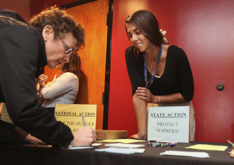 Karen Wentworth, of South Portland, joined by Abby Farnham of the Preble Street Hunger Initiative, signs a card calling for action on dealing with hunger before showing of the film "A Place at the Table" on Tuesday, April 30, 2013 at the Nickelodeon Theater in Portland.