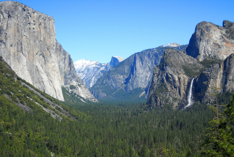 Yosemite Valley as seen from Tunnel View with three of the park’s best-known natural attractions: El Capitan summit on the left, the granite peak known as Half Dome in the distant center and Bridalveil Fall on the right.