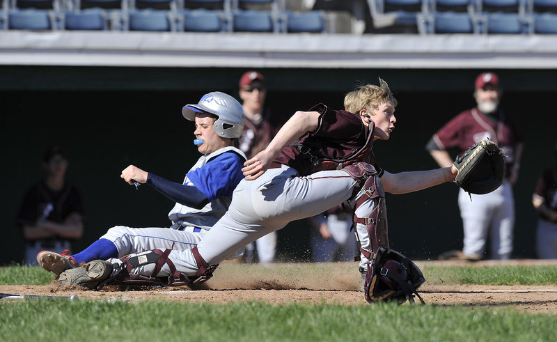 Sean McDermott of Old Orchard Beach slides across the plate in the first inning Wednesday as Freeport catcher Brian Rhea awaits the throw. Rhea hit a two-run single in the seventh inning as Freeport rallied to a 7-4 victory at The Ballpark.