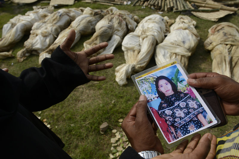 A woman shows a picture of her sister in hopes of finding her body among unclaimed remains in preparation for a mass burial on Wednesday in Dhaka, Bangladesh.
