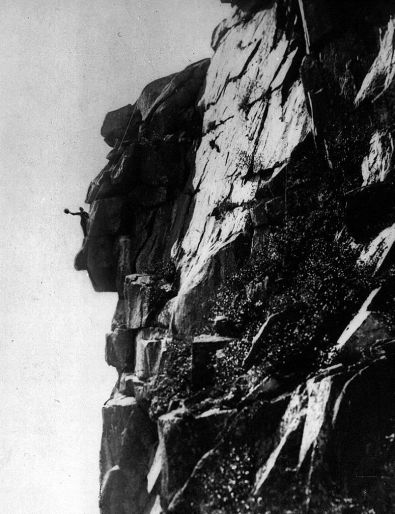 In this 1916 photo provided by the Littleton Area Historical Society, Edward Geddes waves his hat a he stands on the chin of the Old Man of the Mountain in Franconia, N.H. Geddes, a stone quarry superintendent from Quincy, Mass., was the first man to do repair work on New Hampshire's iconic figure, which fell nearly ten years ago. (AP Photo/Littleton Area Historical Society, Rev. Guy Roberts)