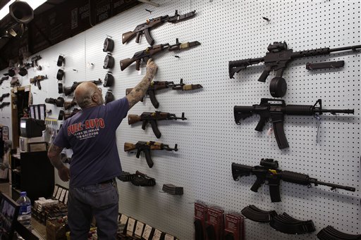 Mel Bernstein takes down an AK-47 assault rifle from a sales rack at his Dragonman’s gun store, east of Colorado Springs, Colo. Federal law requires background checks on gun sales in stores like Bernstein’s but exempts private sales. Efforts to expand background checks have foundered in Washington, but Maine legislators now have a chance to make up for the impasse at the federal level.