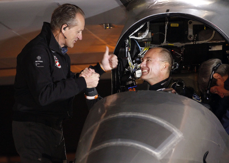 Andre Borschberg, left, and Bertrand Piccard shake hands before the Solar Impulse plane takes off on a multi-city trip across the United States.