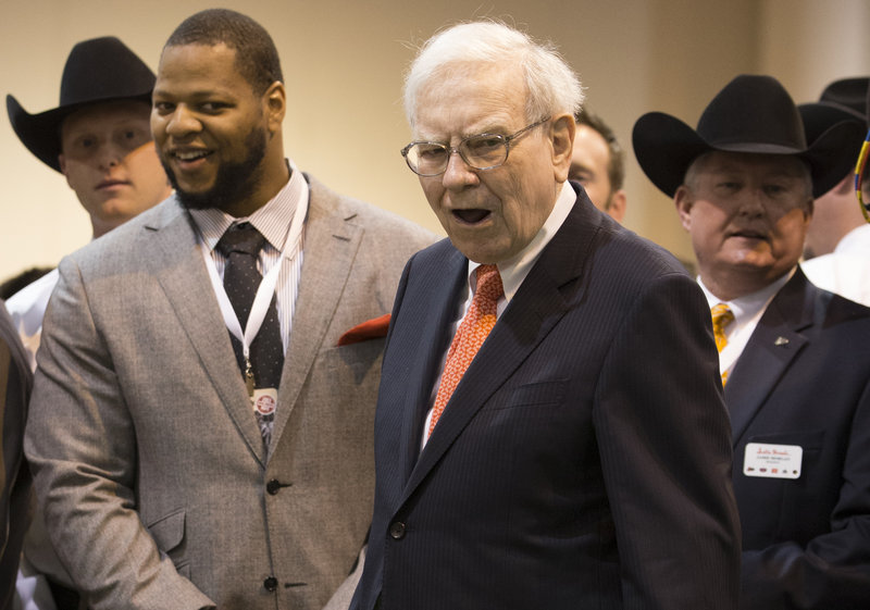 Warren Buffett and Detroit Lions Defensive tackle Ndamukong Suh react as Buffett misses a putt at the Justin Boots booth Saturday. Justin Boots, a Berkshire subsidiary, was promoting its new line of golf shoes.