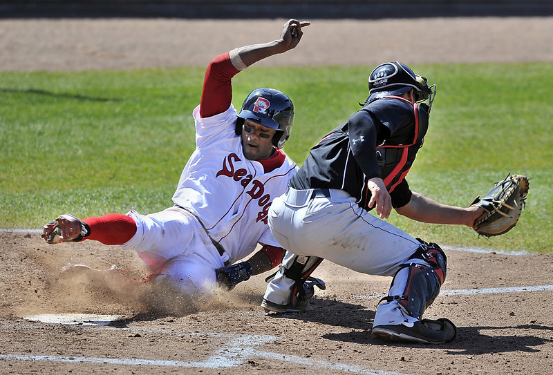 Portland’s Tony Thomas slides around catcher Dan Rohlfing to tie the game at 1-1 after leading off the seventh inning with a double during Saturday’s 2-1 victory.