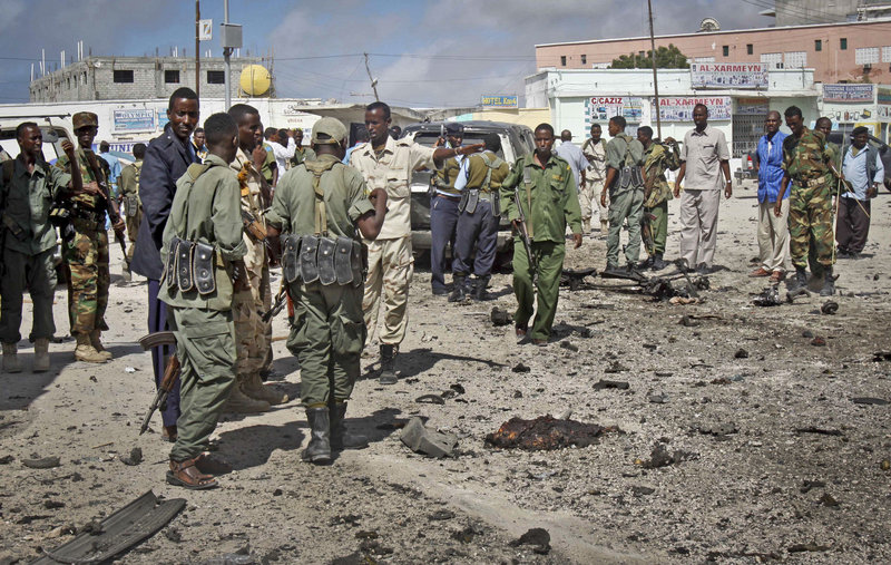 Somali soldiers gather at the scene of a suicide car bombing in Mogadishu on Sunday. Police said the bomber tried to ram a car laden with explosives into a military convoy.