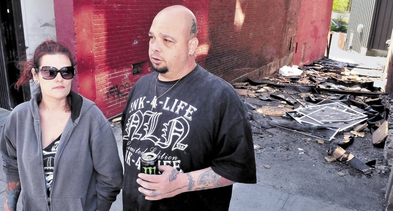 Mona and Bill Juliano, owners of INK-4-LIFE tattoo parlor, speak outside an alley Monday that was littered with debris from the fire that destroyed their business . They are relocating across Main Street.