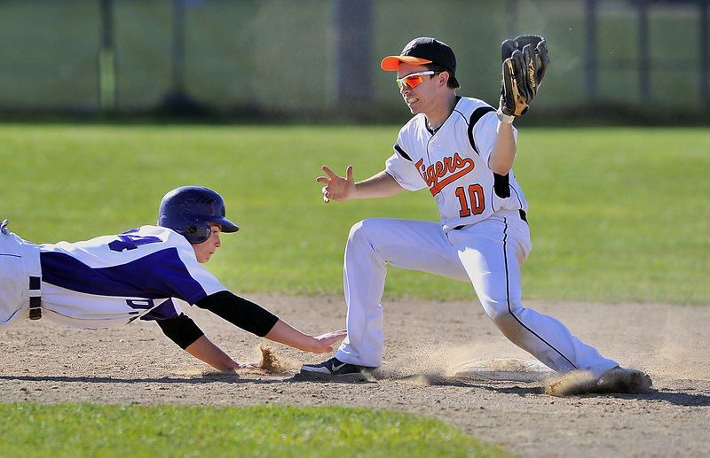 Will Barlock of Deering dives for the safety of the second-base bag Tuesday as Corey Collard of Biddeford takes the throw from the catcher during their SMAA game. Biddeford scored in the bottom of the seventh inning for a 5-4 victory.