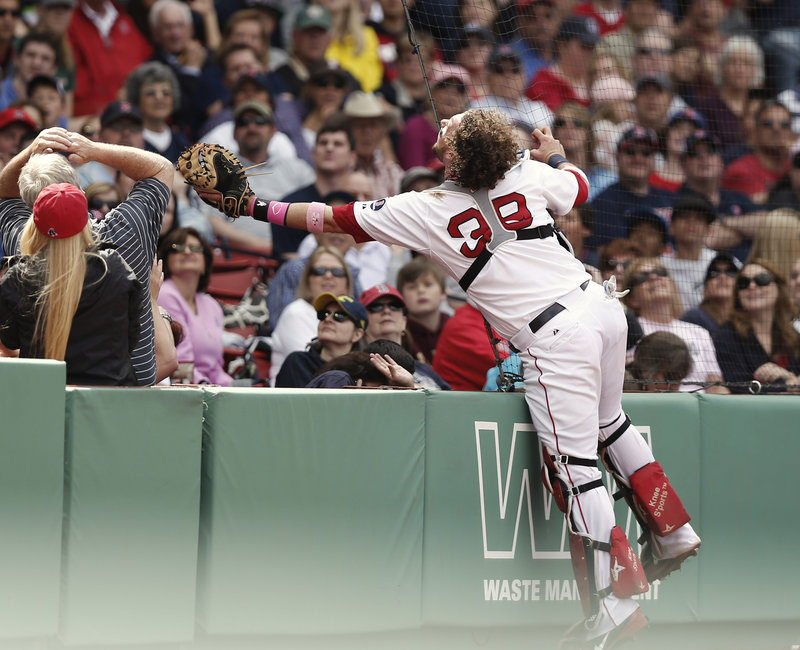 It’s a stretch for Boston catcher Jarrod Saltalamacchia as he unsuccessfully reaches into the stands for a foul popup that lands some rows beyond his glove during the fourth inning of Sunday’s loss to the Toronto Blue Jays at Fenway Park.
