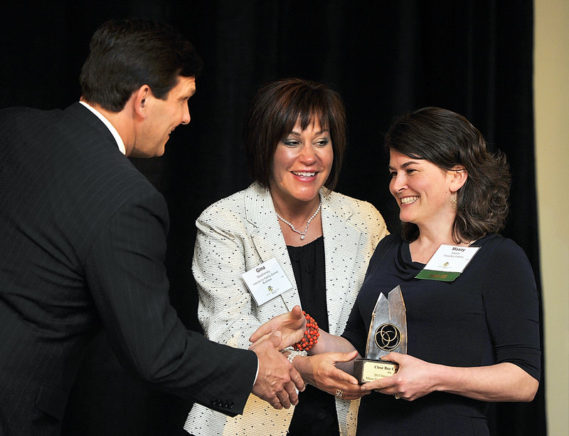 Masey Kaplan, right, receives the 2013 innovation award for her family business, Close Buy Catalog. Giving the award is emcee Gregg Lagerquist, a WGME-TV news anchor, and Gina Weathersby, executive director of the Institute for Family-Owned Business.