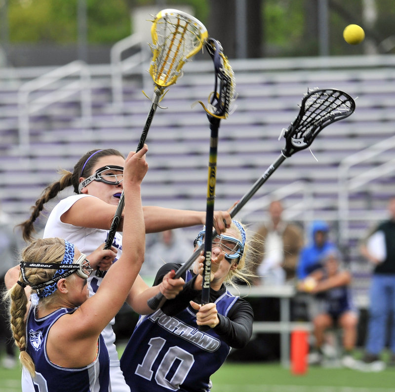 Julianna Salamone of Deering fires a shot between two Portland defenders – Hallie Alex, left, and Cole Spike – in a Class A lacrosse game at Deering’s Memorial Field. Portland won, 13-5.