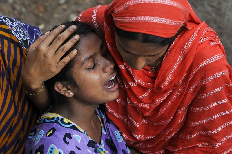 A woman cries last week after identifying the body of her father at a makeshift morgue near the site of a Bangladesh clothing factory’s April 24 collapse. American companies’ participation is critical to the success of an accord committing clothing retailers to hiring safety inspectors for and upgrading their factories in Bangladesh.