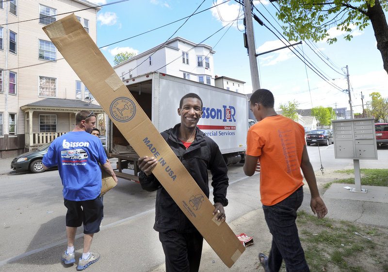 Mohamed Mohamed, 17, smiles as he carries a bed frame into the apartment building.
