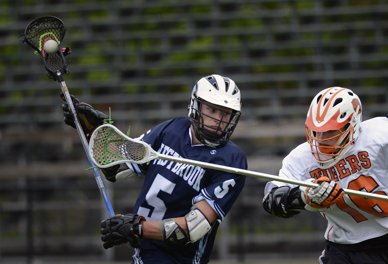 Ben Grant of Westbrook High drives the ball down the field Wednesday as Callum Maloy of Biddeford moves in to defend during their SMAA schoolboy lacrosse game at Biddeford.