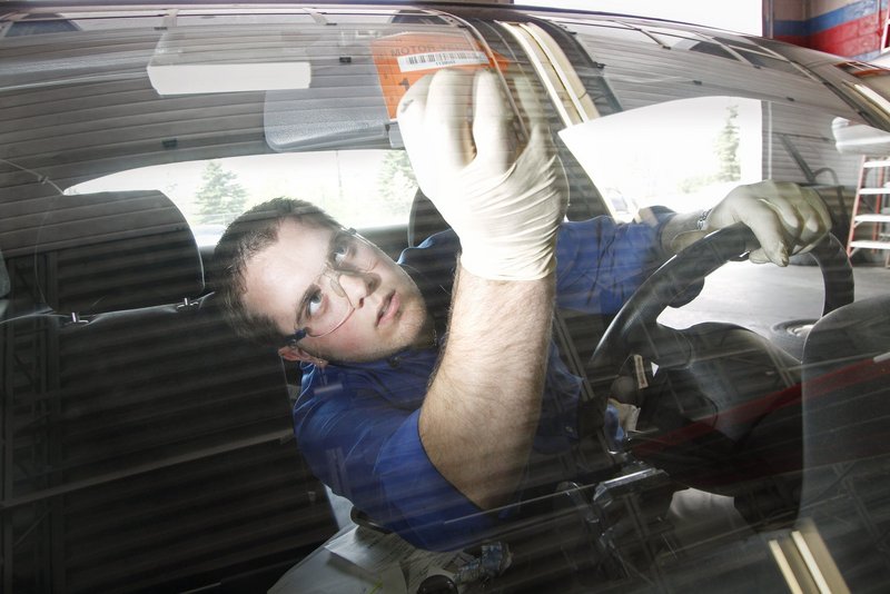 Erik Lowell of AAA Car Care in Portland puts a new sticker on a car after he inspected and passed the vehicle in 2011. A reader says Maine’s car inspection mandate amounts to “a regressive tax.”