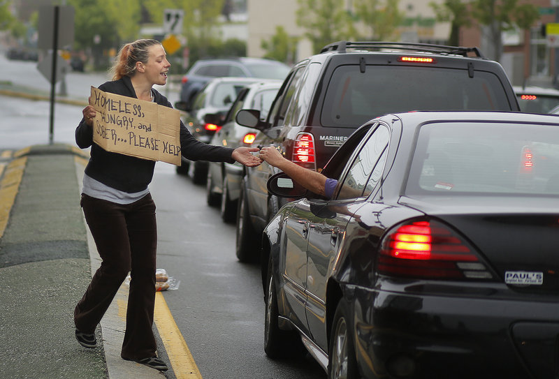 Alison Prior, 29, of Portland, receives change from a passerby while she panhandles at the corner of Preble Street and Marginal Way on Friday, May 24, 2013. Prior says she panhandles for extra money while she and her boyfriend look for an apartment.