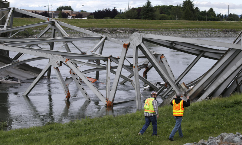 Workers walk past the collapsed Interstate 5 bridge in Mount Vernon, Wash., on Friday