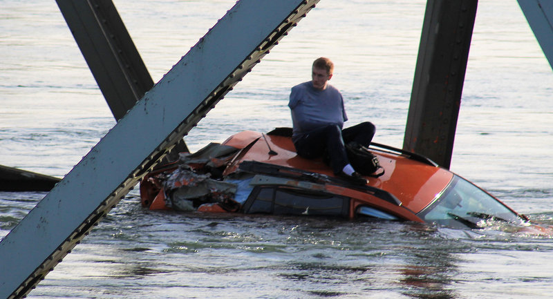 A man, at left, awaits rescue atop a car that fell into the Skagit River, in a photo provided by Francisco Rodriguez.