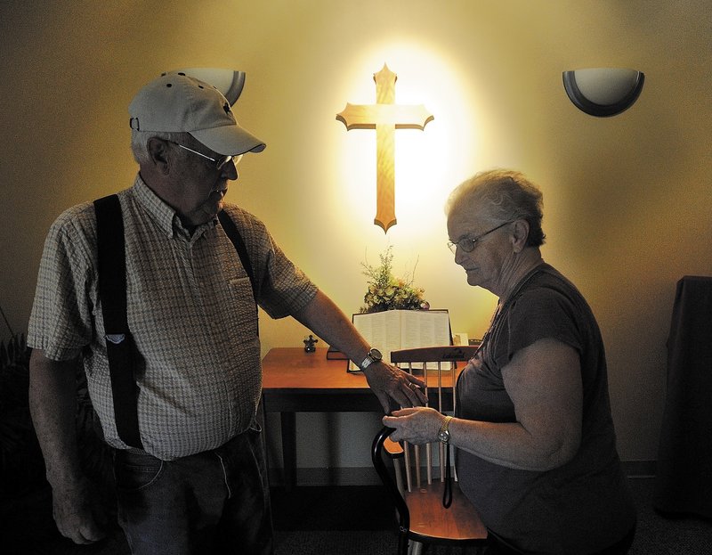 Gerald "Jake" Ellis, 79, reaches for the hand of his wife, Pauline Ellis, 79, in the chapel at Lakewood Nursing Home in Waterville Wednesday. A resident of the home's dementia ward, Pauline Ellis has enjoyed improved quality of life after being taken off antipsychotic drugs.
