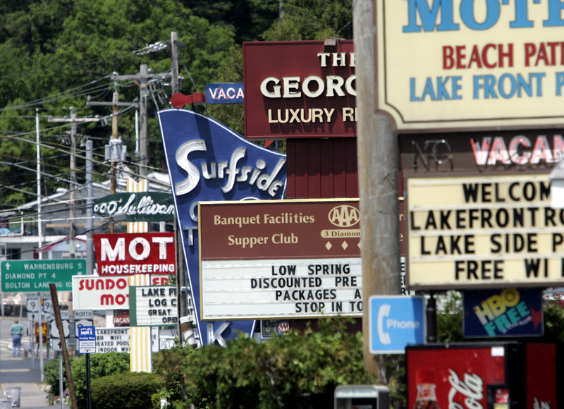 Motel signs line a road in Lake George, N.Y., a popular vacation destination. Airlines, hotels and campgrounds are likely to see slightly more customers in 2013 than in the previous few summers, according to travel industry forecasters.