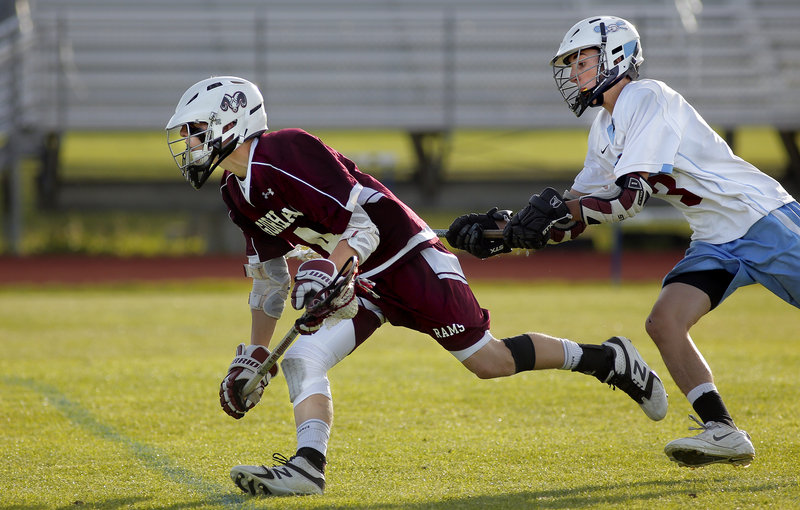 Caleb Dolloff of Gorham keeps his footing Tuesday while advancing past Zack Callahan of Windham during their schoolboy lacrosse game at Windham High. Gorham pulled away to a 14-4 victory.