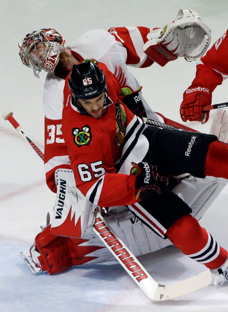 Andrew Shaw of the Blackhawks collides with Red Wings goalie Jimmy Howard in Game 7 on Wednesday night in Chicago. The Blackhawks won in overtime, 2-1.