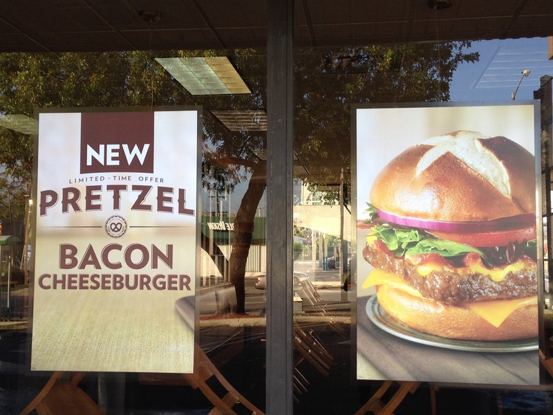 A pretzel bacon burger is pictured in a promotional sign in the window of a Wendy’s restaurant.