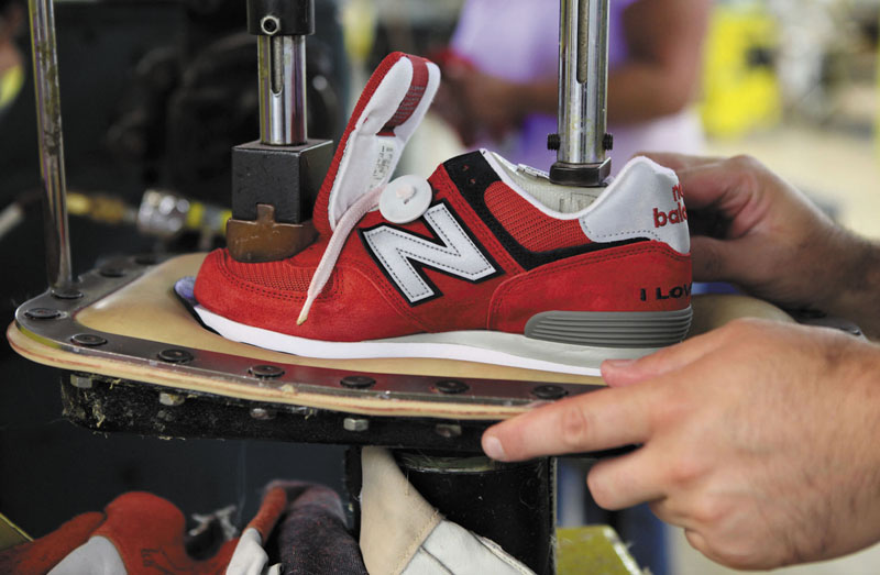 A worker uses a press to attach a shoe upper to the outsole at the New Balance factory in Norridgewock. Rep. Mike Michaud last week successfully amended an omnibus defense bill to require that the nation's military equip new recruits with sneakers manufactured in the U.S.
