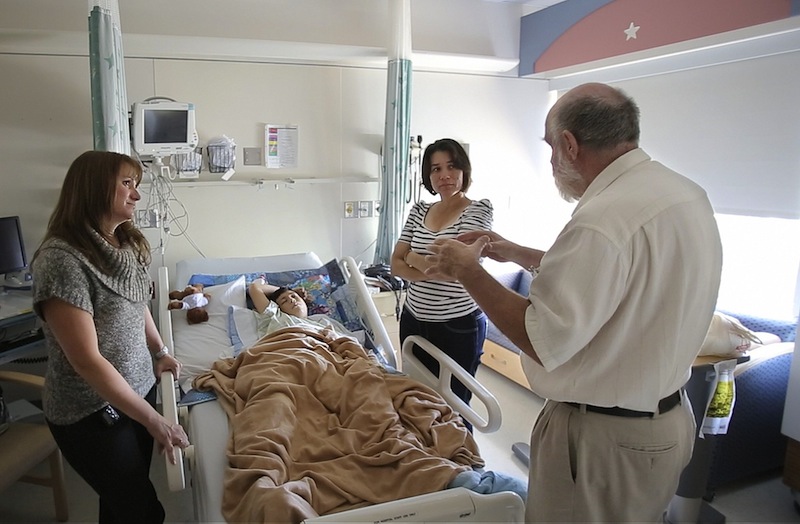 In this September 2012 file photo, interpreter George Bentley talks to Rina Yadira Galan with instructions and advice from Nurse Practioner Nicole Mizner, at left, before a young patient is discharged from Maine Medical Center in Portland. The cost of free care provided by Maine hospitals to uninsured patients has more than doubled since 2007, and those expenses will continue to grow unless Maine Medicaid expansion becomes law, hospital officials said.