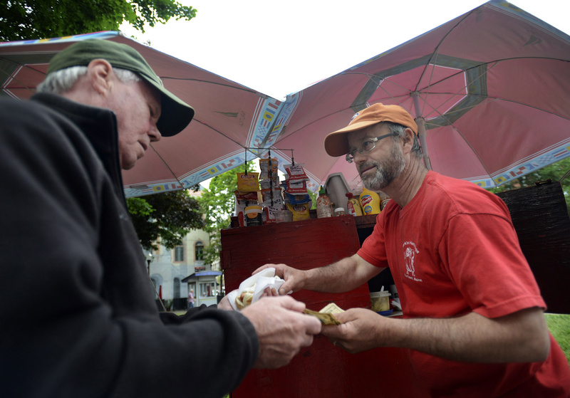 Mark Gatti of Mark's Hot Dogs, right, serves a frank to Bob Fitzgerald of Westbrook on Monday. For three decades, Gatti has served hot dogs plain and fancy - even during snowy winter weather – in Portland's Old Port.