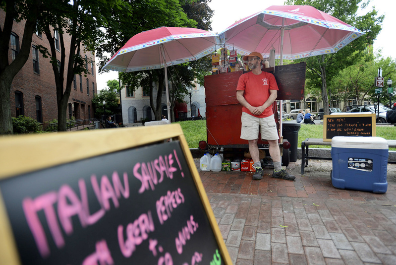 Mark Gatti is ready to serve customers at his Mark's Hot Dogs stand Monday. He and his father built the red food cart from which Gatti has sold more than 840,000 hot dogs.