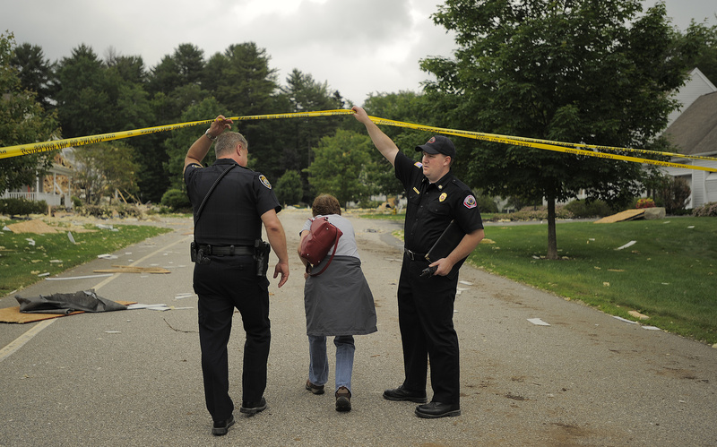 Dee Dyer-Reich ducks under police tape at Gables Drive in Yarmouth Wednesday, as she goes to retrieve medication from her father's condo that was damaged in the Tuesday blast.