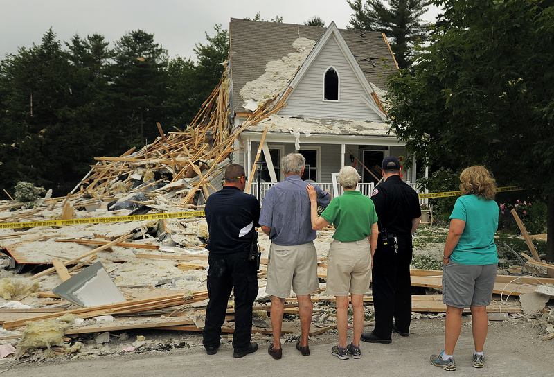 Rosemary MacKay comforts her husband, Robert, in blue, Wednesday afternoon as they survey the remains of their house at 52 Gables Drive in Yarmouth. The structure was condemned after an explosion on Tuesday killed their neighbor, Peter Corey, and severely damaged their house, along with others on the street. At left is Yarmouth fire chief Michael Robitaille, and at right is deputy chief Rich Kindelan, along with the MacKay's daughter, Alison Moore, at far right.