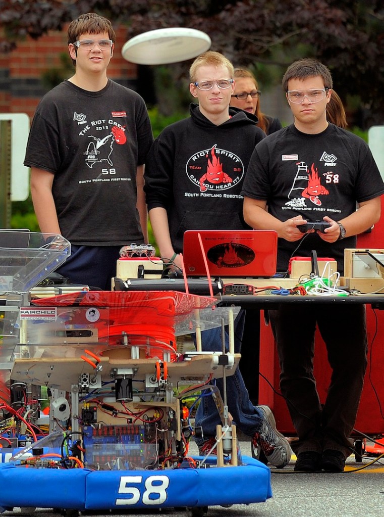 Members of the South Portland Robotics team, left to right, Alex Manning, Ross Usinge and Aaron Davies, watch as a Frisbee flies out of their robot at Fairchild Semiconductor in South Portland on Thursday. Gov. Paul LePage and inventor Dean Kamen were on hand.