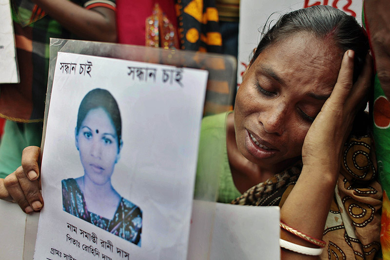 A Bangladeshi woman holds a paper with a photograph of a missing relative as she pleads for help and calls for compensation for the more than 1,100 workers who were killed in a garment-factory building collapse in April.