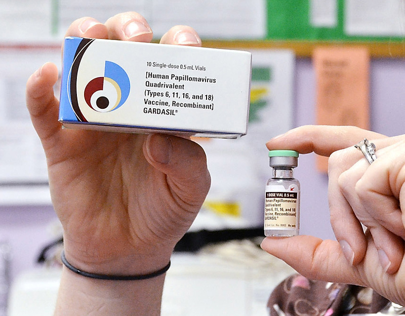 A nurse holds up a vial and box for the HPV vaccine Gardasil.