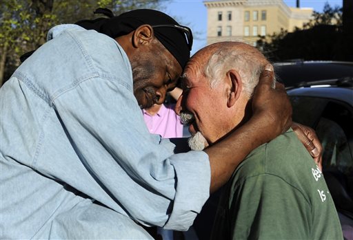 In this May 1, 2013, photo, Michael Johnson, left, hugs friend Anthony Cymerys in Bushnell Park in Hartford, Conn.