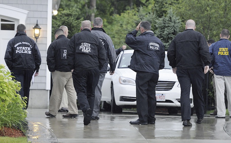 In this Tuesday, June 18, 2013 photo, state and local police gather outside the home of New England Patriot's NFL football player Aaron Hernandez in North Attleborough, Mass. Police spent hours at the home Tuesday as another group of officers searched an industrial park about a mile away where a body was discovered the day before. (AP Photo/The Sun Chronicle, Martin Gavin)