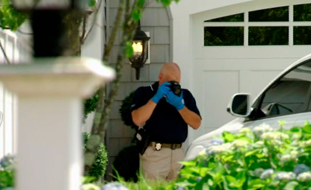 In this image taken from video, a police officer photographs a car outside the home of New England Patriots football player Aaron Hernandez, Saturday, June 22, 2013, in North Attleboro, Mass. State police officers and dogs searched Hernandez's home as they investigate the killing of Odin Lloyd, a semi-pro football player whose body was found nearby. (AP Photo/ESPN)