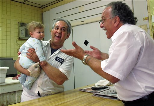 John Sacco Sr. hands his 6-month-old grandson, Jack Russo, to Pete Canu, a customer in Sacco's Elizabeth, N.J., butcher shop, Thursday. Canu says he liked the realism and human flaws of actor James Gandolfini's Tony Soprano character, but Sacco said, "The Sopranos perpetuated and spread negative stereotypes about Italian-Americans."