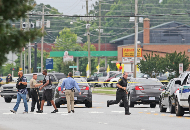 Police investigate the scene of a shooting Friday in Greenville, N.C. A man armed with a shotgun wounded one person at a law firm, then shot three more people across the street in a Walmart parking lot.
