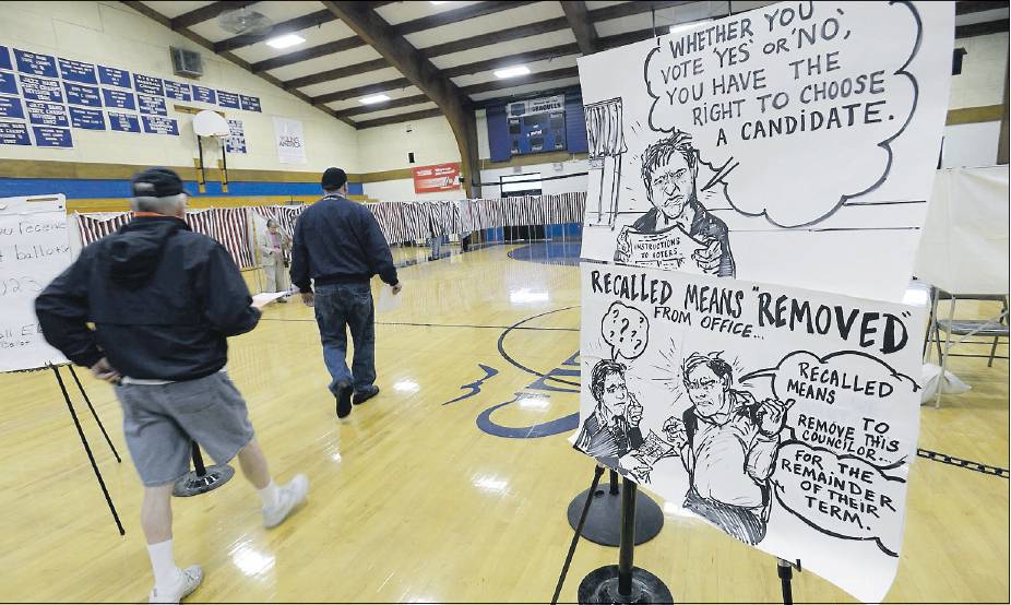 Residents make their way to the voting booths Tuesday at Old Orchard Beach High School, passing signs about councilor voting and explaining what a recall means. The signs were created by Channing Reeves, who lives in town.