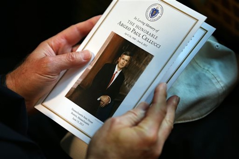 A man holds a program during a remembrance for Cellucci Thursday in Boston.