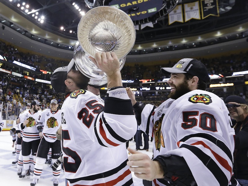 Chicago Blackhawks left wing Viktor Stalberg (25), of Sweden, hoists the Stanley Cup alongside goalie Corey Crawford (50) after the Blackhawks beat the Boston Bruins [score] in Game 6 of the NHL hockey Stanley Cup Finals Monday, June 24, 2013, in Boston. (AP Photo/Elise Amendola) TD Garden