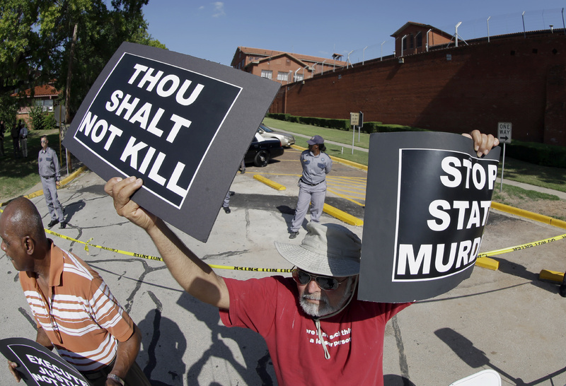 Habi Jawad holds up his signs to protest the execution of Kimberly McCarthy on Wednesday outside the Texas Department of Criminal Justice Huntsville Unit, where the death chamber is located, in Huntsville, Texas.