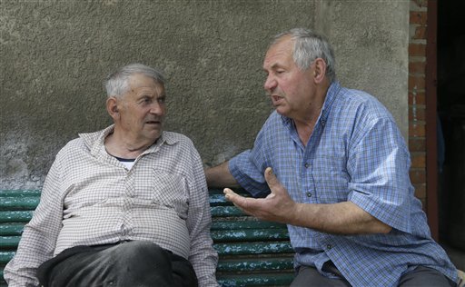 In this May 10, 2013, photo, Heorhiy Syvyi, 78, left, and Ivan Hrushka share their war memories in their home village of Pidhaitsi close to Ukraine's western city of Lutsk. Nearly two dozen civilians, primarily women and children, were slaughtered in Pidhaitsi. Evidence uncovered by AP indicates that Ukrainian Self Defense Legion commander Michael Karkoc's unit was in the area at the time of the massacre.
