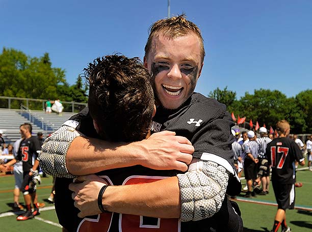 A smiling Austin Doody hugs teammate Luke Bernard after Scarborough won its fourth straight Class A state championship.
